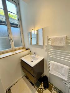 a white bathroom with a sink and a window at Appartement cosy Centre ville in Moulins