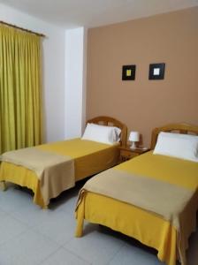 two beds in a hotel room with yellow sheets at Apartamentos Martell in Playa de Santiago