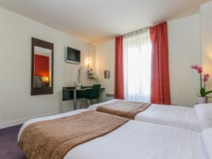 ein Hotelzimmer mit zwei Betten und einem Tisch in der Unterkunft Hotel Arc Paris Porte d'Orléans in Montrouge