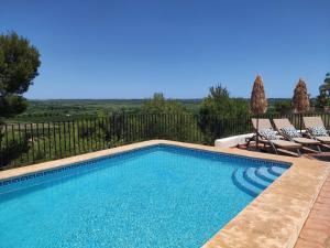 a swimming pool with two lounge chairs next to it at Holiday home Monte Pego in Monte Pego