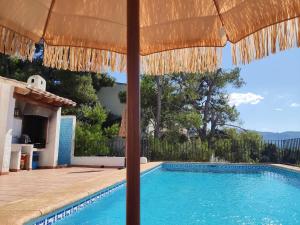 a villa with a swimming pool and an umbrella at Holiday home Monte Pego in Monte Pego