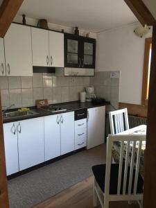 a kitchen with white cabinets and a table and a chair at Apartments Novela in Poljanak