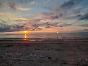 a view of a beach with the sun setting over the ocean at Kristof701 in De Panne +5 photos