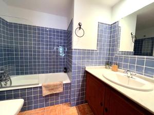 baño de azulejos azules con bañera y lavamanos en Apartamentos Deluxe Espot, en Espot