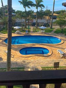 a large swimming pool in a yard with palm trees at Apart hotel a 150m da praia de Geribá in Búzios