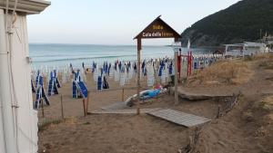 uma praia com cadeiras de praia azuis e o oceano em B&B Dionea em Santa Maria di Castellabate