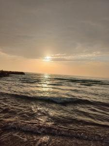a beach with the sun setting over the ocean at Bylis Rooms in Golem +21 photos