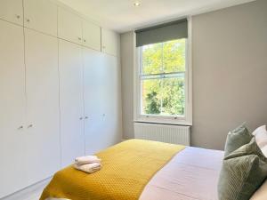 a bedroom with a bed with a yellow blanket and a window at 2 Bedroom Apartment in South Hampstead in London