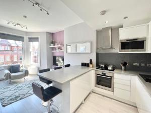 eine Küche mit weißen Schränken sowie einem Tisch und Stühlen in der Unterkunft 2 Bedroom Apartment in South Hampstead in London