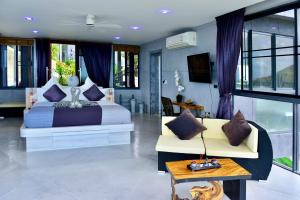 a bedroom with a bed and a couch and windows at Paradise Villa Elysium in Koh Samui