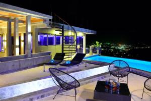 een patio met stoelen en 's avonds een zwembad bij Paradise Villa Elysium in Koh Samui 