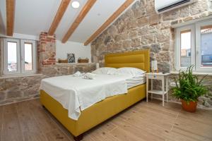 sypialnia z żółtym łóżkiem w kamiennej ścianie w obiekcie Maki Stone House - Parking on request ! w Splicie