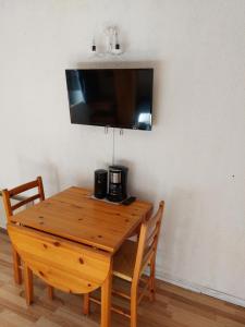 een houten tafel met twee stoelen en een televisie aan de muur bij Appartement vacances à la montagne - Massif des Brasses in Bogève