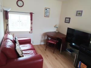 a living room with a red leather couch and a television at Haven Apartments in Whitehaven