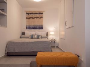 una camera con letto e ottomana gialla di Up the stairs renovated apartment with sea view a Poros