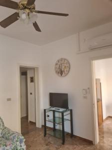 a ceiling fan in a living room with a table and a clock at casa al mare kalispera in Marina di Mancaversa