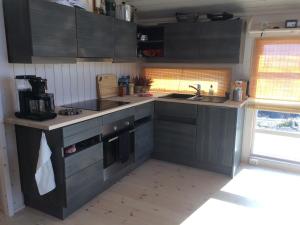 a kitchen with black cabinets and a sink at Hytte på Sørbølfjellet in Flå