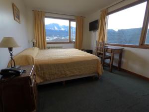 ein Hotelzimmer mit einem Bett und einem großen Fenster in der Unterkunft OIKOS in Ushuaia