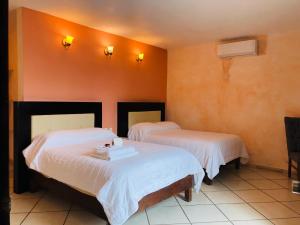 1 dormitorio con 2 camas con sábanas blancas en Hotel Camino Surreal Xilitla en Xilitla