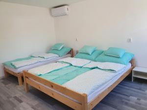 two beds in a room with blue pillows at Família Apartman Cserkeszőlő in Cserkeszőlő