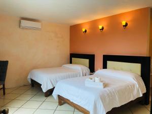2 camas en una habitación con sábanas blancas en Hotel Camino Surreal Xilitla en Xilitla