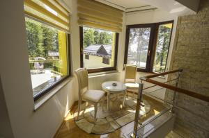 een kamer met 2 stoelen, een tafel en ramen bij Villa Forest Sarajevo in Sarajevo