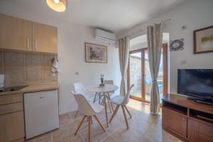 a kitchen with a table and chairs and a television at Apartments Franovic in Perast