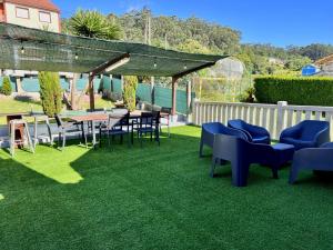 a patio with chairs and tables on the grass at Descanso Natural Bueu in Bueu