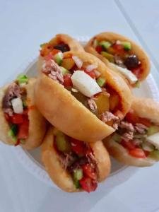 trzy hot dogi na papierowym talerzu na stole w obiekcie בקתה בכרם BH w mieście Nevatim