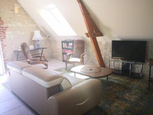 a living room with a couch and a tv at La Longère du Val in Tauxigny