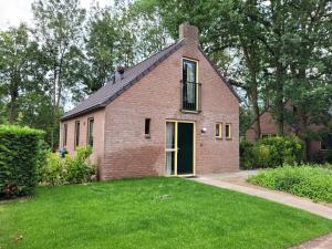 a brick house with a green lawn in front of it at Retro Chic Wellness met hottub & sauna in Ewijk