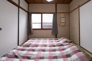 a bedroom with a bed with a checkered blanket at Ikkenya Tsushima in Okayama