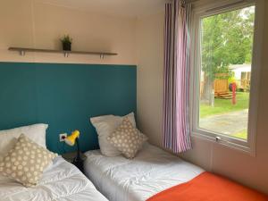 a room with two beds next to a window at Cosy Lili - Mobilhome MANDARINE - Proche océan in Saint-Georges-de-Didonne