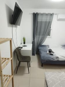 a small bedroom with a bed and a desk and a chair at Apartment with terrace and parking in Eilat