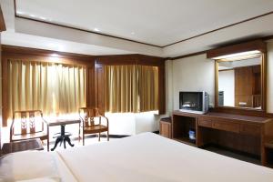 Habitación de hotel con cama, escritorio y TV. en The A.A. Pattaya Residence, en Pattaya central