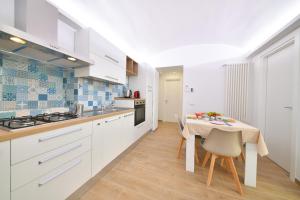 a kitchen with white cabinets and a table with chairs at Casa GLEM in Ischia