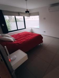 1 dormitorio con cama roja y ventana en Departamentos Kairos H en Mendoza