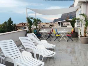 um grupo de cadeiras e mesas brancas numa varanda em Nerissa suites&rooms em Terrasini
