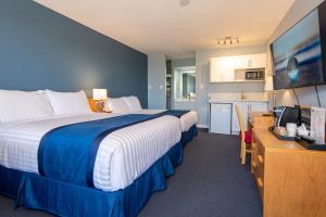 a hotel room with a large bed and a kitchen at Ocean Crest Motel in Qualicum Beach