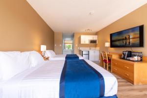Habitación de hotel con cama grande y cocina en Ocean Crest Motel, en Qualicum Beach