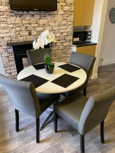 a table with two chairs and a table with flowers on it at Hilltop Place Suites Flat Above 250 in Sheffield