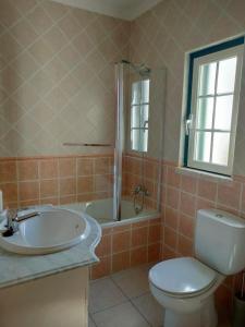 a bathroom with a toilet and a tub and a sink at A casa do Almograve in Almograve