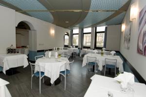 un ristorante con tavoli e sedie bianchi e finestre di Hotel Europa a Sondrio