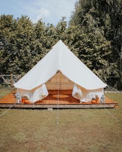 a white tent with a wooden deck in a field at Rubeni in Stāķi