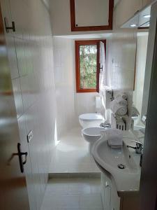 a white bathroom with two sinks and two toilets at La casa di Elisa in Vinci