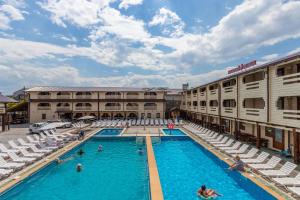 a hotel pool with chairs and people in it at Золотий Павлін in Solotvyno