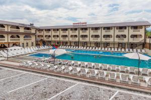 a hotel with a large swimming pool with white chairs at Золотий Павлін in Solotvyno