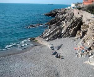 a beach with some rocks and the ocean at Casa marina in Genoa