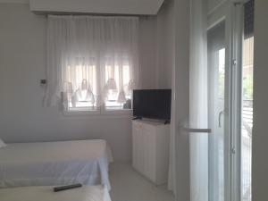 a white room with two beds and a television at Annas seaside apartment in Perea