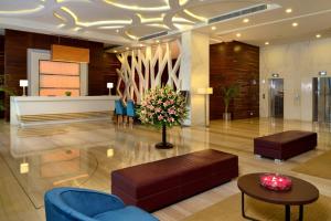 a lobby with blue chairs and a table and flowers at Golden Tulip Lucknow in Lucknow